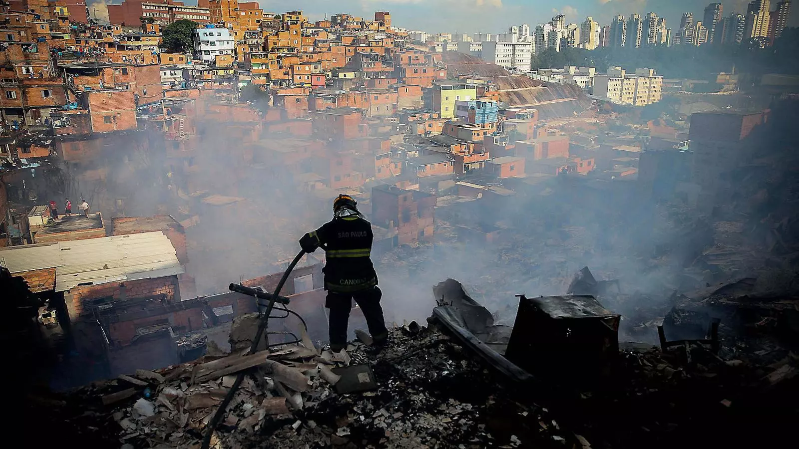 Un bomber intentant apagar un foc en una de les faveles més grans de São Paulo.