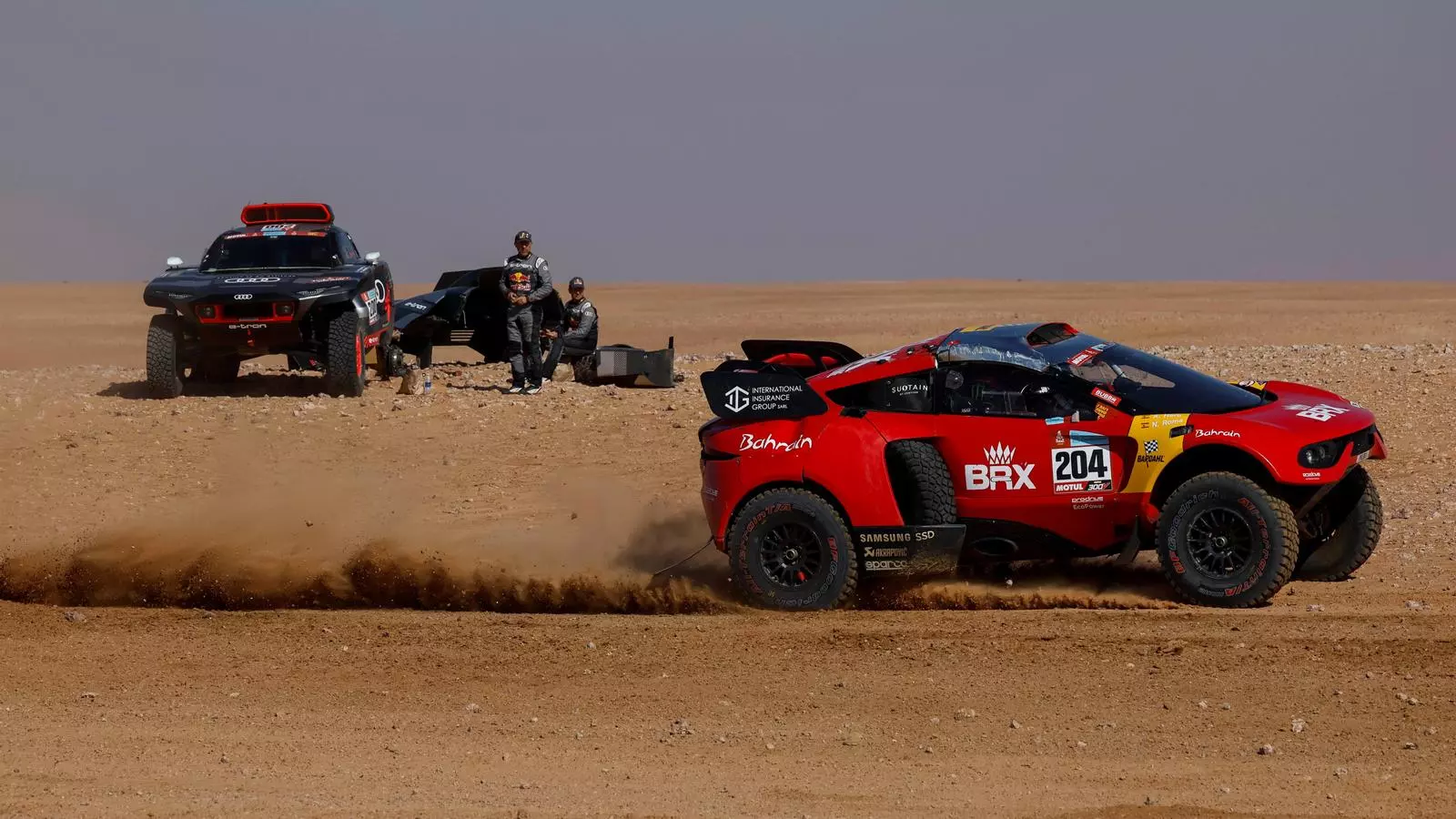 El pilot Nani Roma i el seu copilot Álex Haro Bravo passen prop del vehicle avariat de Stéphane Peterhansel i Edouard Boulanger