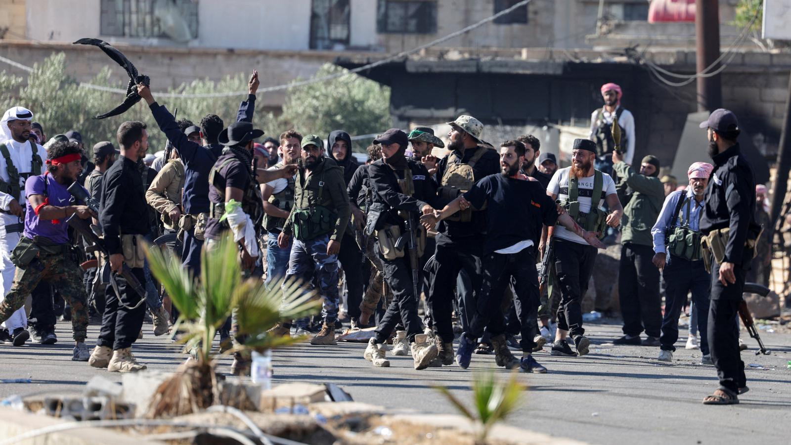 Syrian government agents escort a Druze prisoner and prevent him from being attacked by Bedouin at a checkpoint in Sweida.