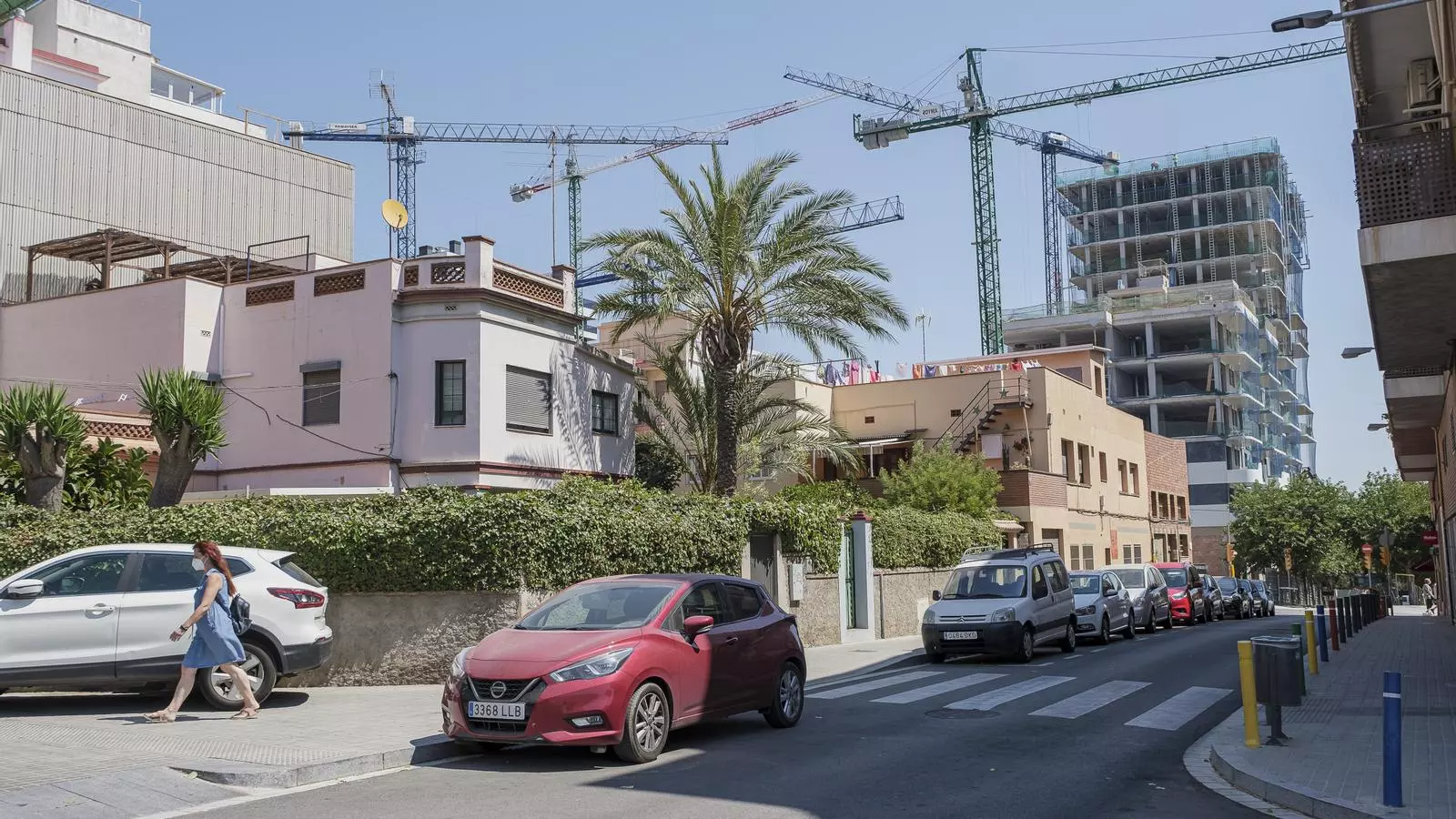 L'edifici de l'escola Sanfeliu, al costat d'uns pisos en construcció, a l'Hospitalet de Llobregat.