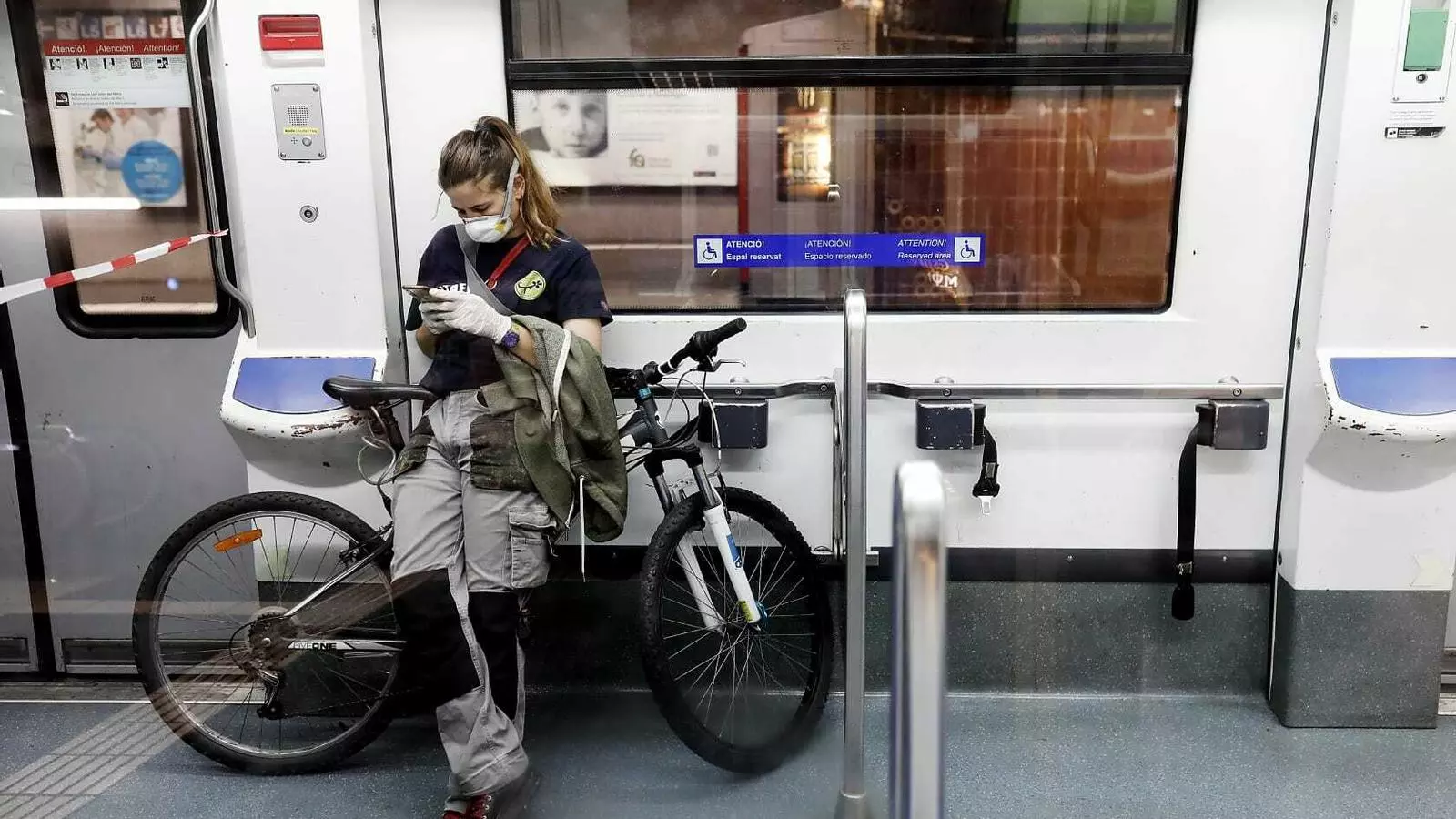 Una treballadora amb mascareta i guants dins d'un vagó de metro el primer dia feiner després que s'hagi aixecat el confinament total