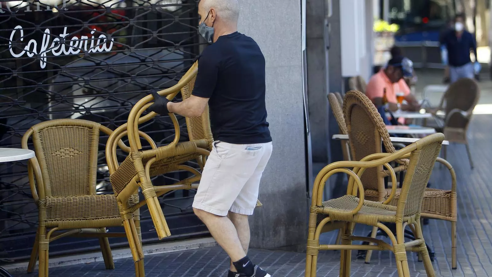 Un cambrer munta taules d'una terrassa a Palma