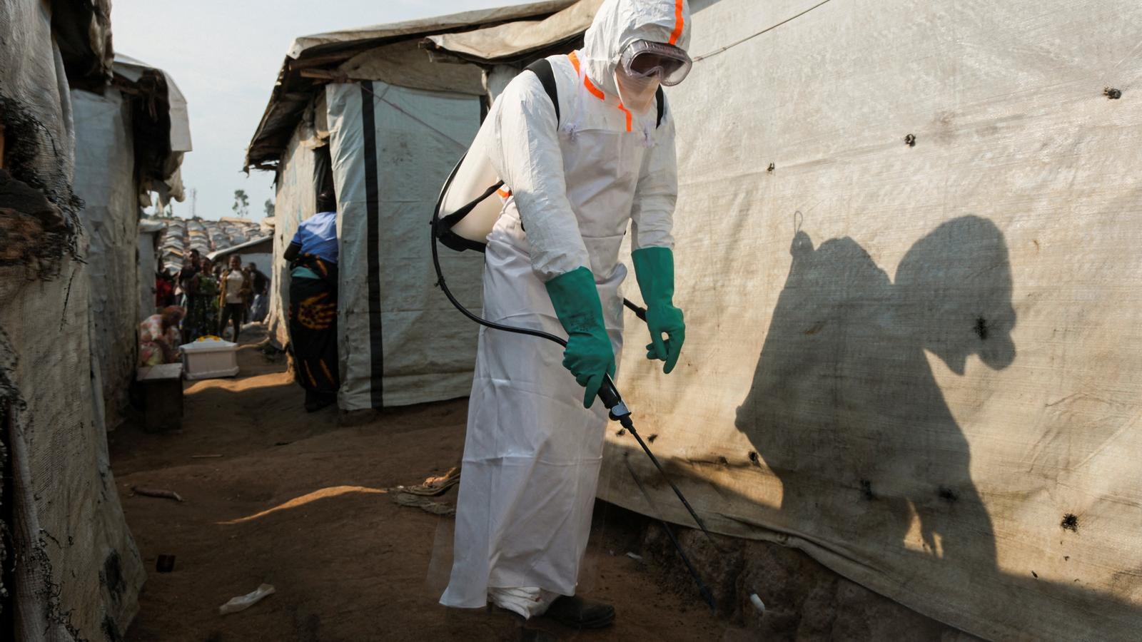 A healthcare worker disinfects the surroundings of a tent in the Kigonze displacement camp, in Bunia, eastern Democratic Republic of Congo.
