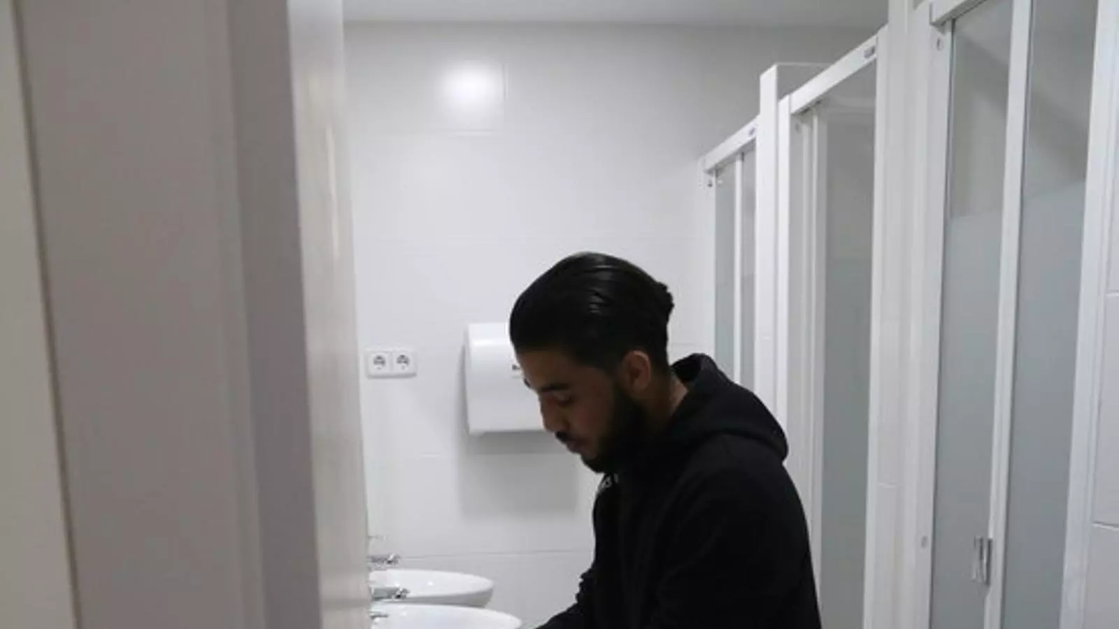 Pla sencer de l'Omar, un jove de 18 anys que viu al centre Maria Feixa, rentant-se les mans al lavabo