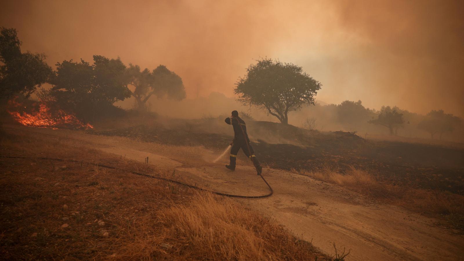 A firefighter works to extinguish the fire in Psatha, about sixty kilometers from Athens.