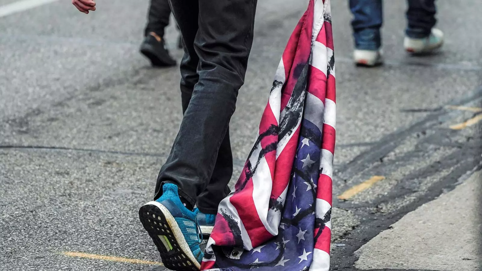 Un manifestant arrossega una bandera dels EUA tacada amb petroli, durant una protesta contra Donald Trumpa Wyoming