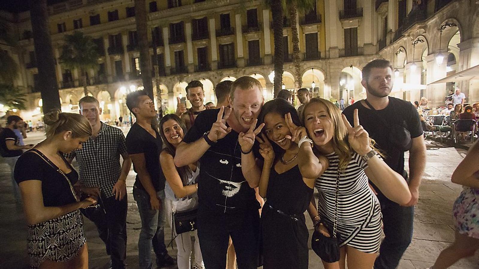 Tourists in Plaza Real while participating in a crawl. Each person pays 15 euros and the company takes them on a tour of several bars to get drunk.