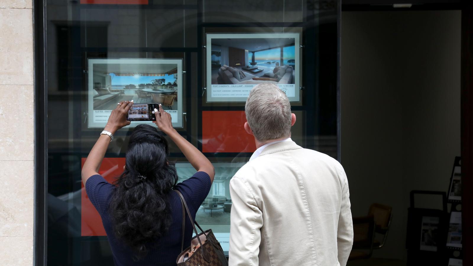 Dos turistas mirando pisos a una inmobiliaria