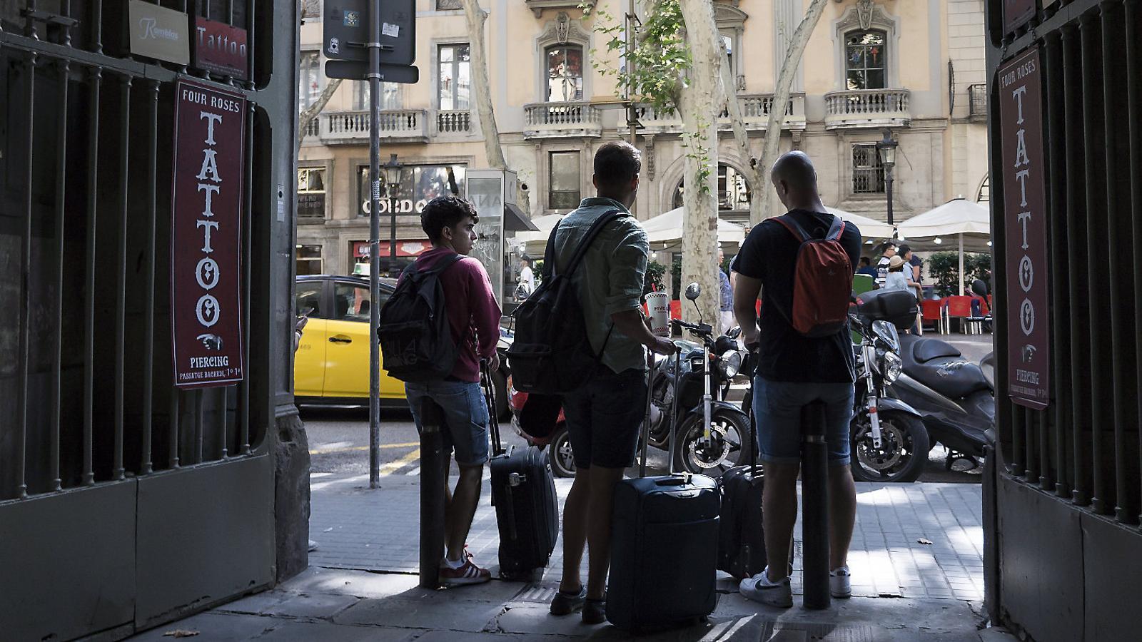 Tres turistas con maletas en la rambla de Barcelona.