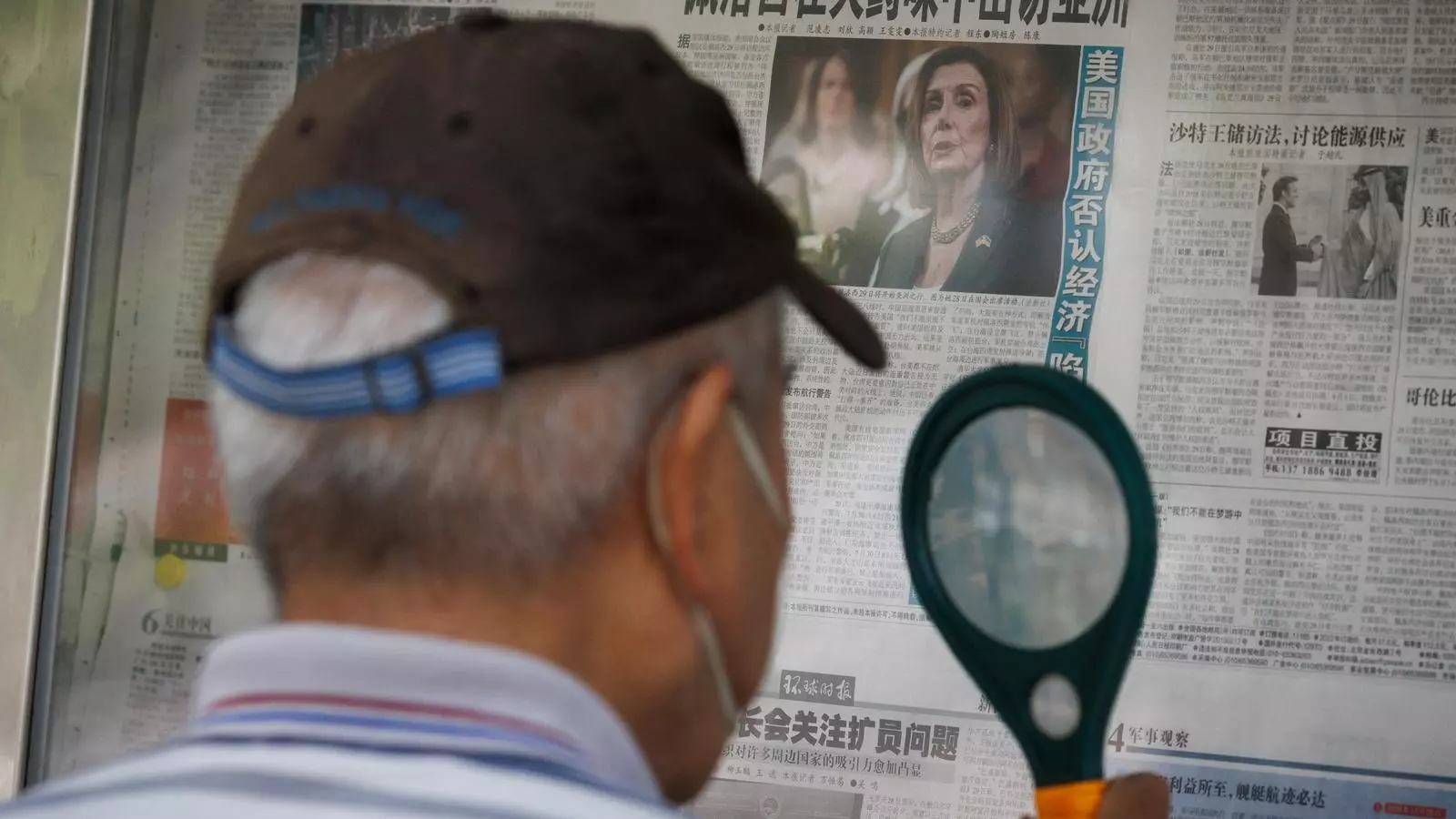 Un hombre lee un diario en Pekín que habla de la gira asiática de Nancy Pelosi con el titular: "Pelosi visita el Asia con aroma de pòlvora".
