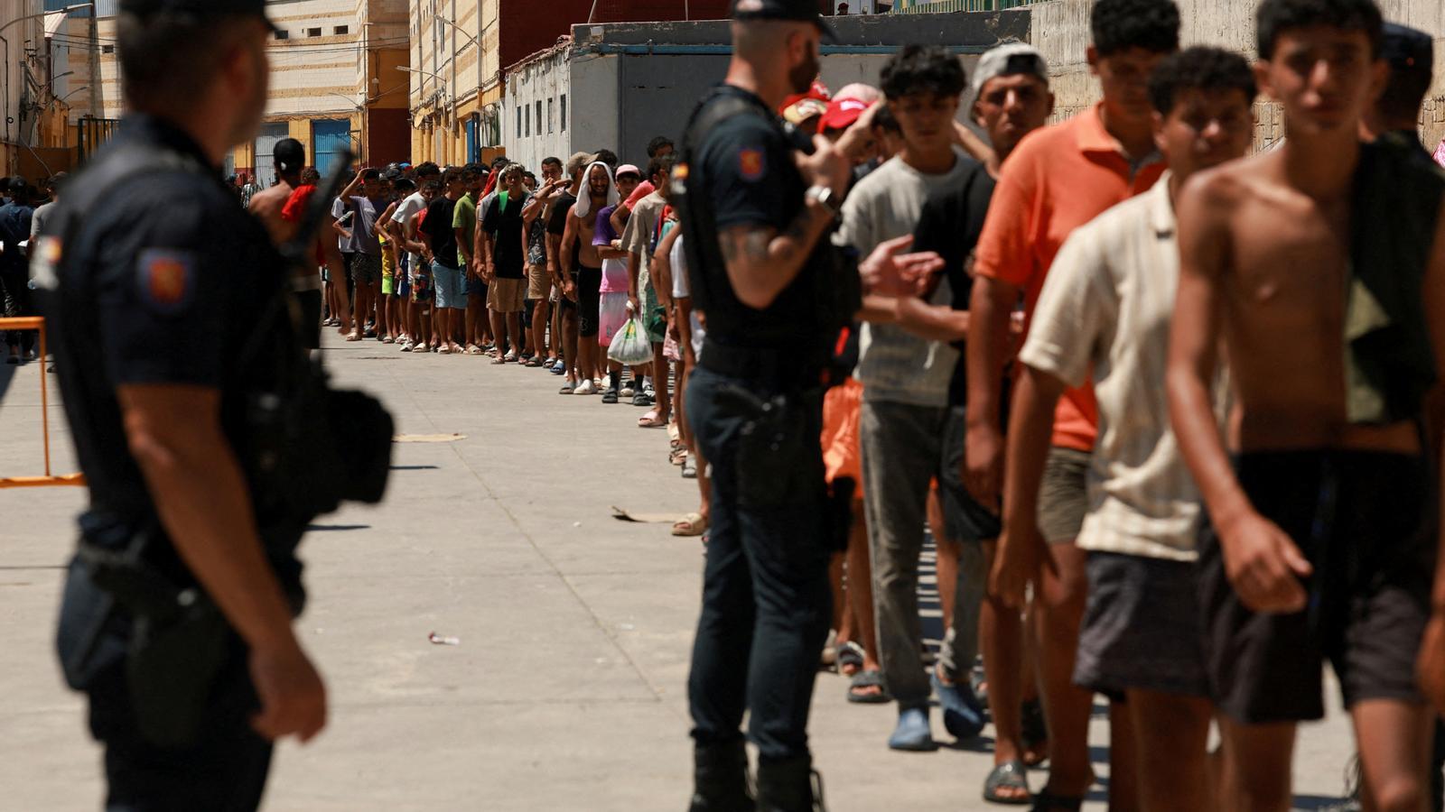 Migrantes hacen cola para recibir comida de la ONG Media Luna Blanca en Ceuta.