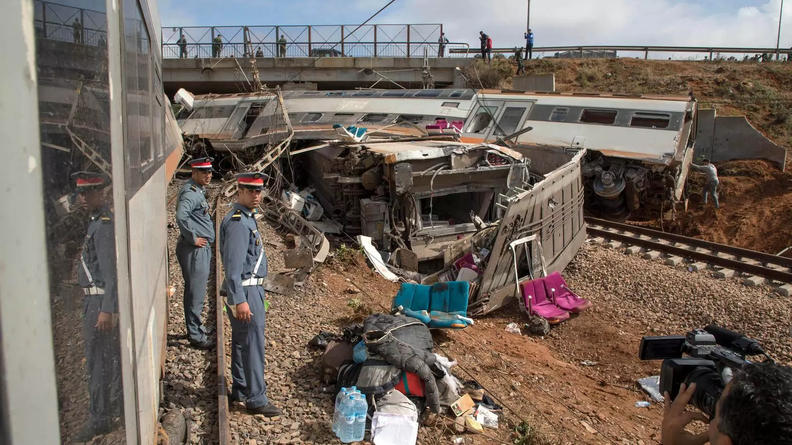 Un vagó descarrilat que ha xocat amb el pont, dues persones dels cossos de seguretat i diferents objectes dels viatgers al lloc de l'accident a la ciutat de Bouknadel.