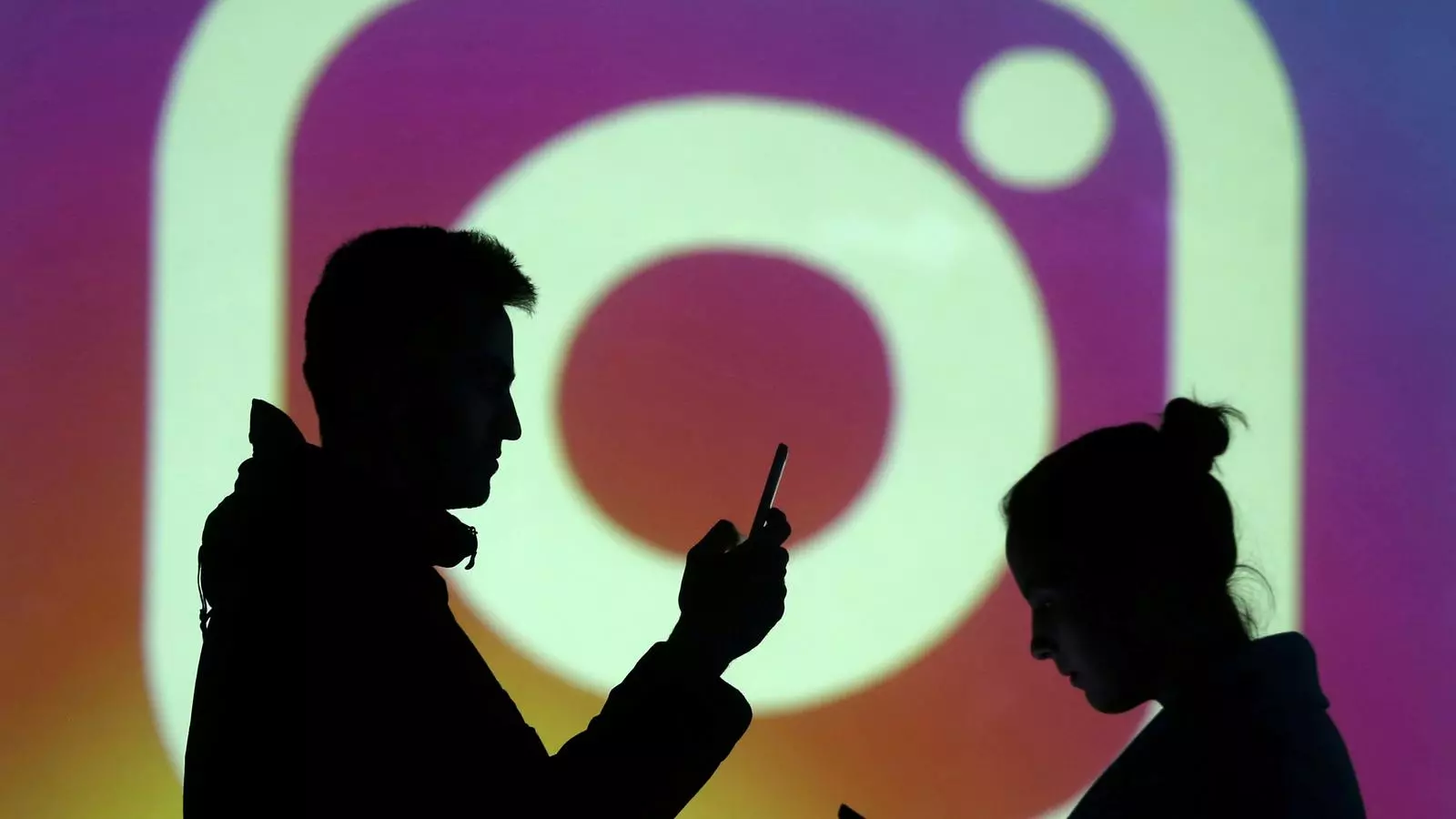 Les siluetes de dues persones amb el logotip d'Instagram al fons