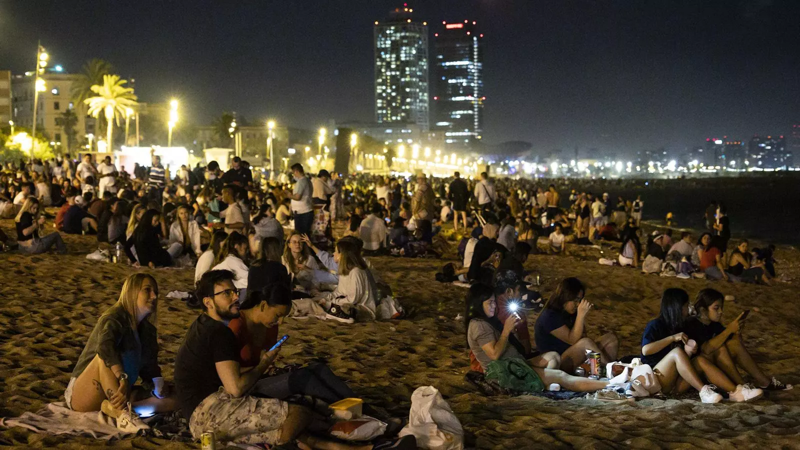 Grupos de personas a la playa de la Barceloneta de Barcelona la noche de la verbena de San Juan.
