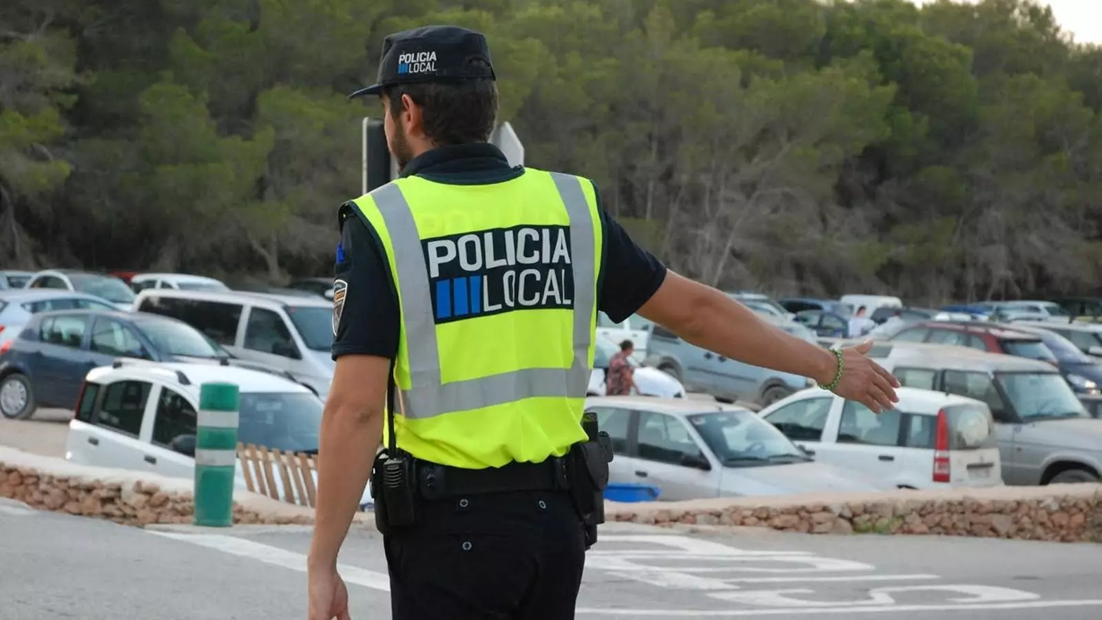 Un policia local controla el trànsit a un aparcament