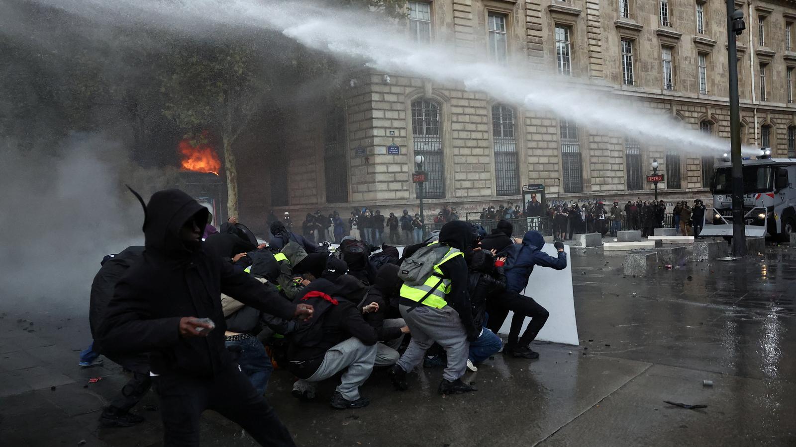 Protesters protect themselves behind a barricade while the police try to disperse them with a water cannon, this Saturday at the Place de la République in Paris.