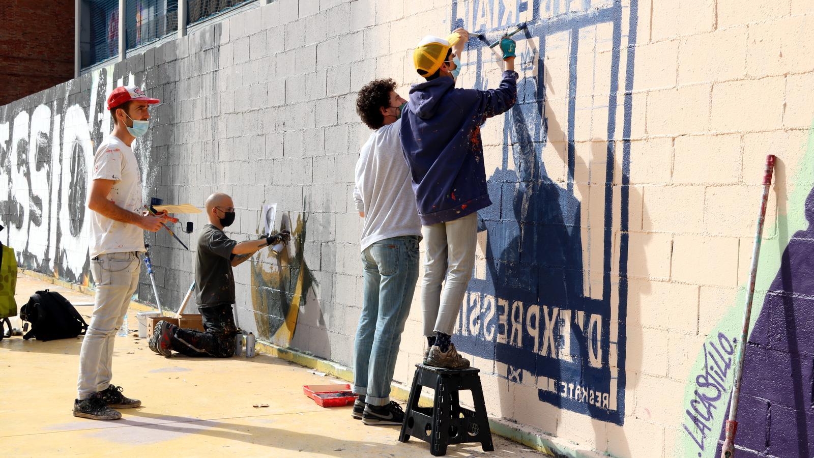Artists making graffiti in support of Hasel on the wall of the passage of the Canadiense