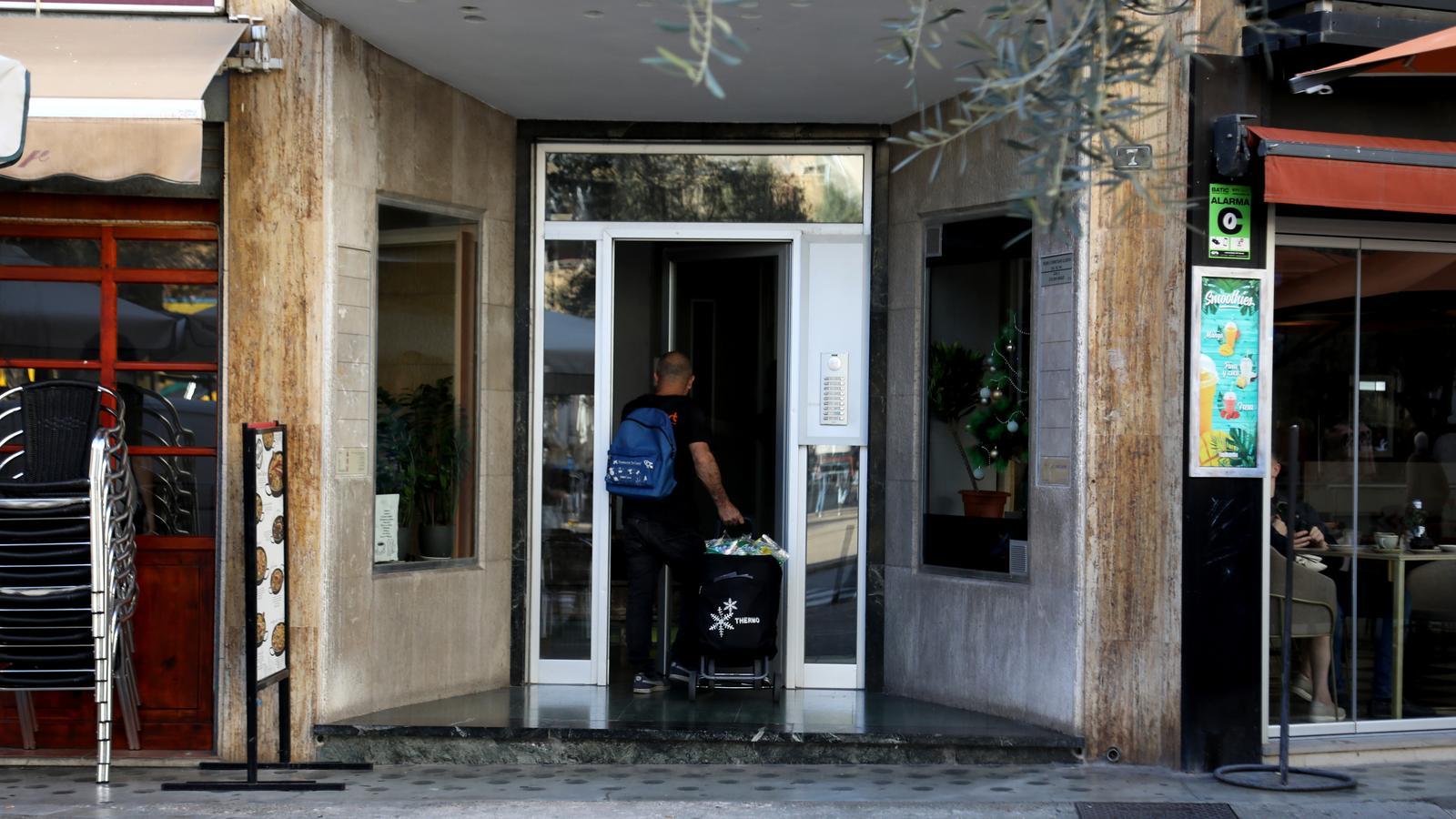 Una persona entra al portal de casa seva amb una compra.