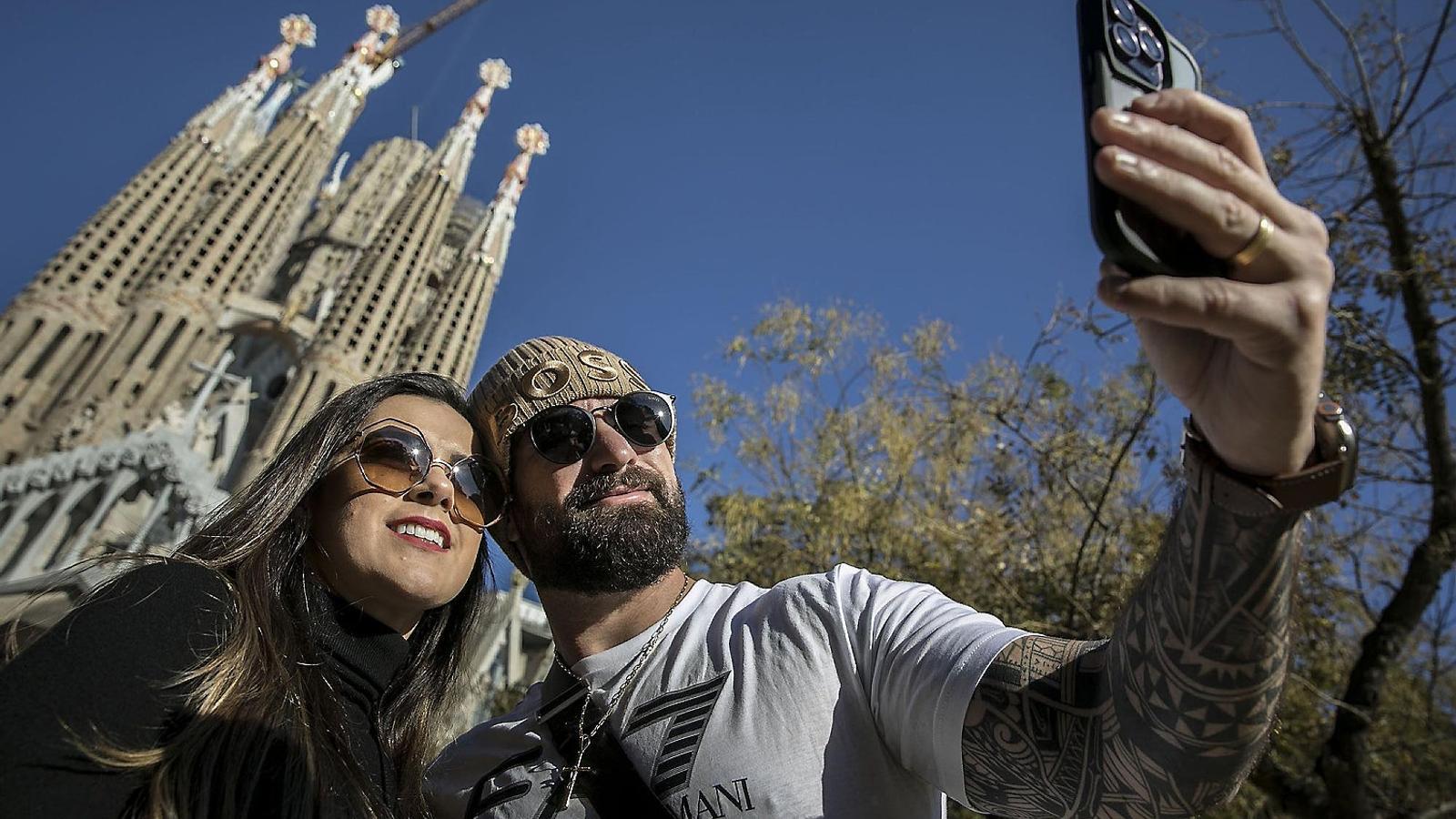Two tourists taking a selfie in front of La Sagrada Familia.