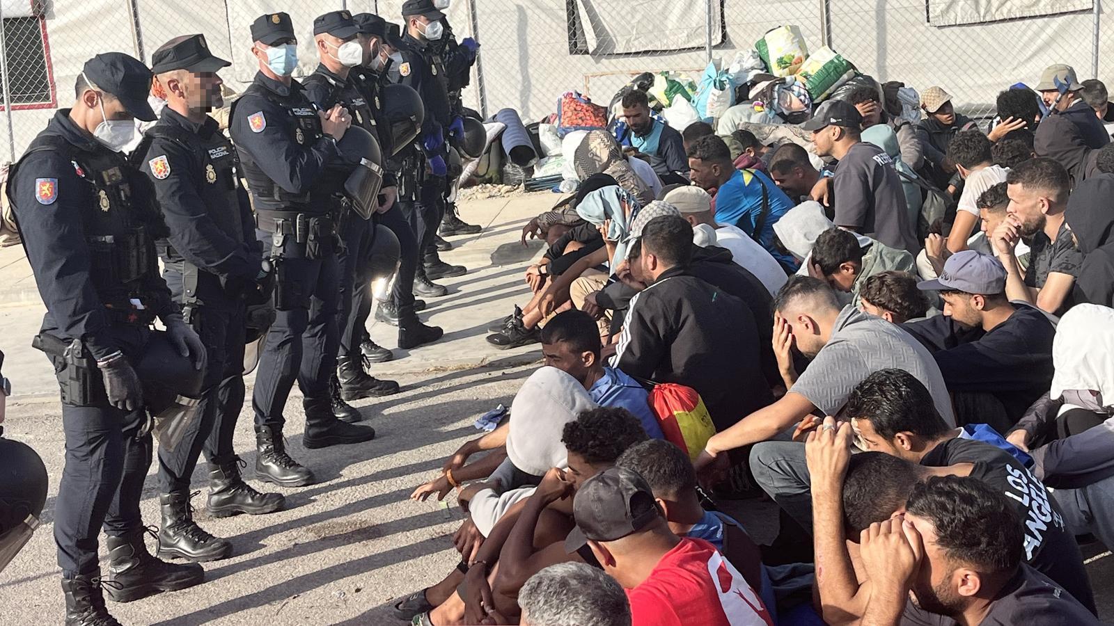 Members of the National Police escort several migrants during the transfer from Loma Colmenar towards the tent area in the Los Rosales area, in Ceuta.