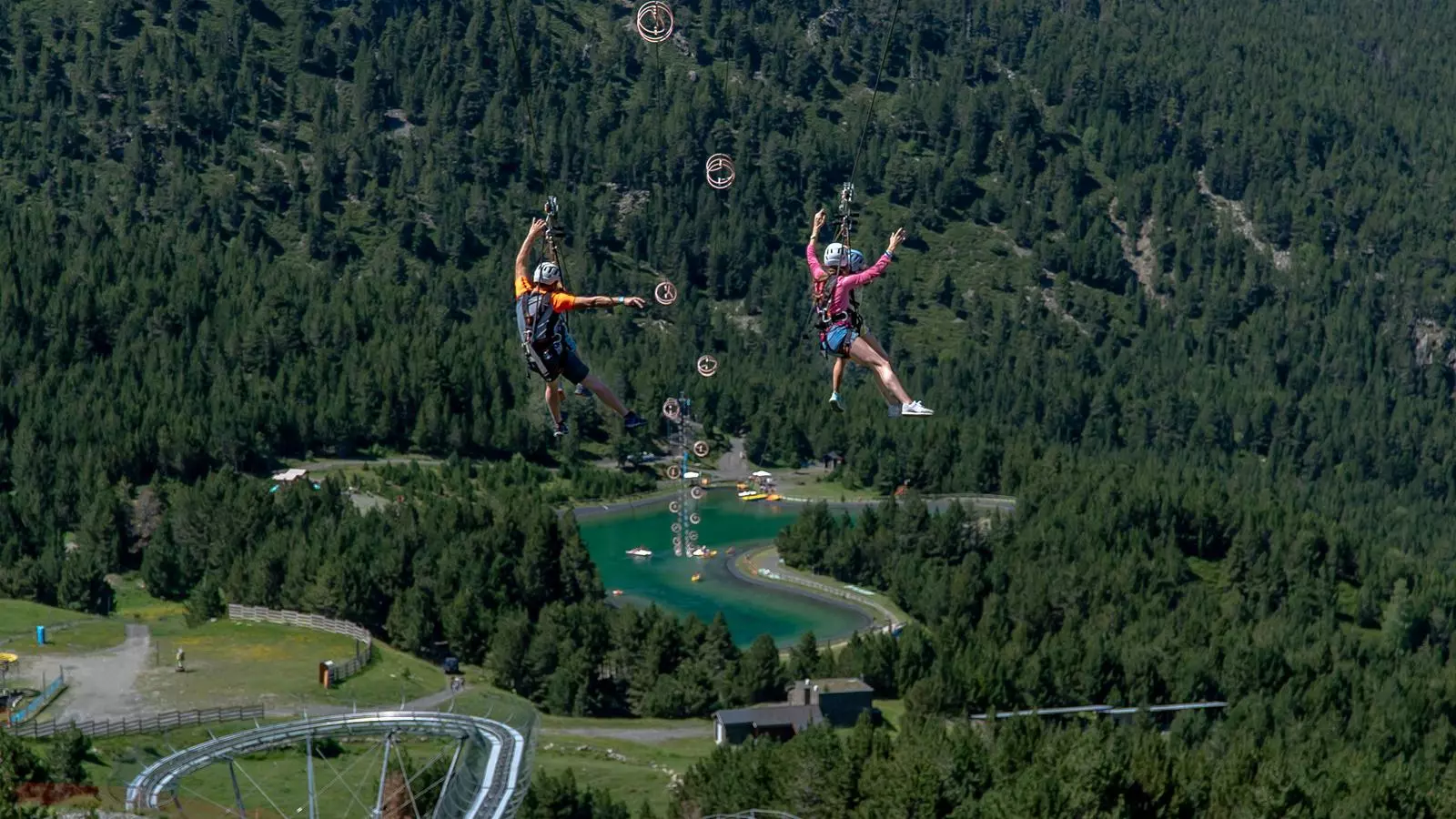 Dos turistes baixant per la tirolina situada al Mon(t) Magic de Canillo.