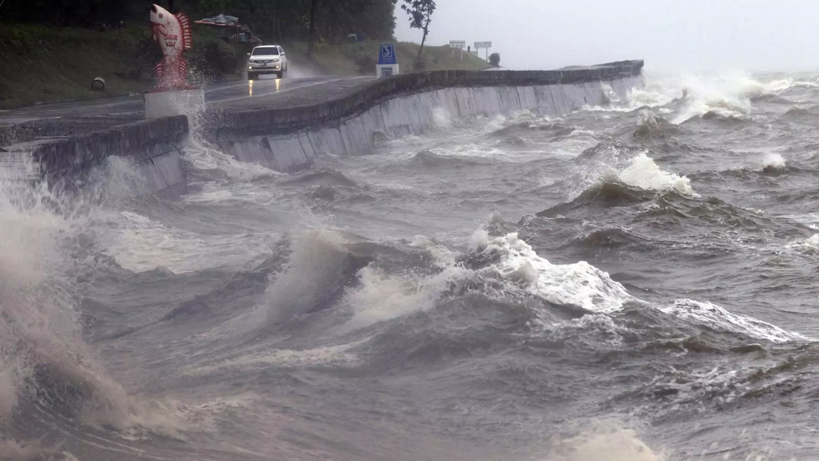 Un cotxe circula per una carretera costanera al costat del mar enfurit a Atimonan, la província de Quezón / REUTERS