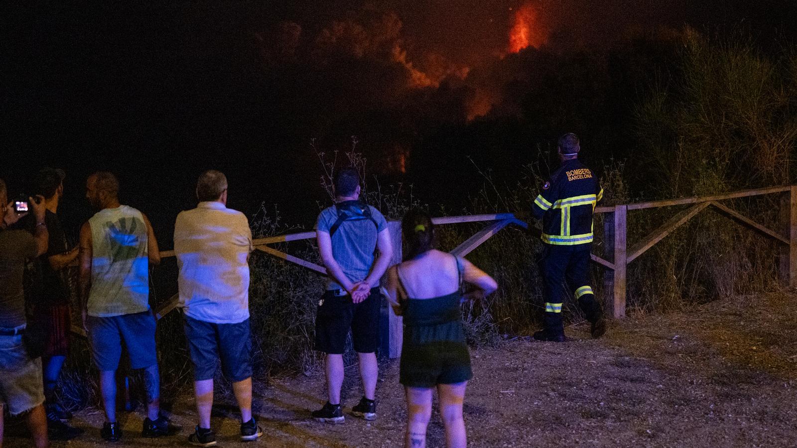 Bomberos y vecinos de Ciutat Meridiana observan el incendio.
