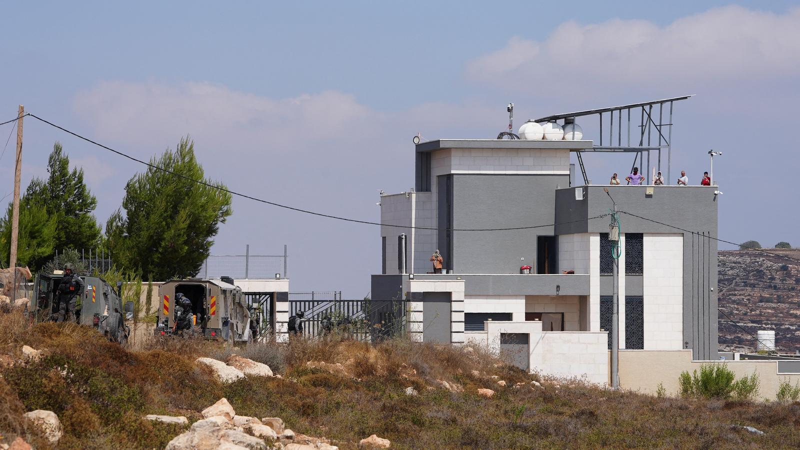 Members of Israeli security forces guard in front of a Palestinian house in Qusra, West Bank.