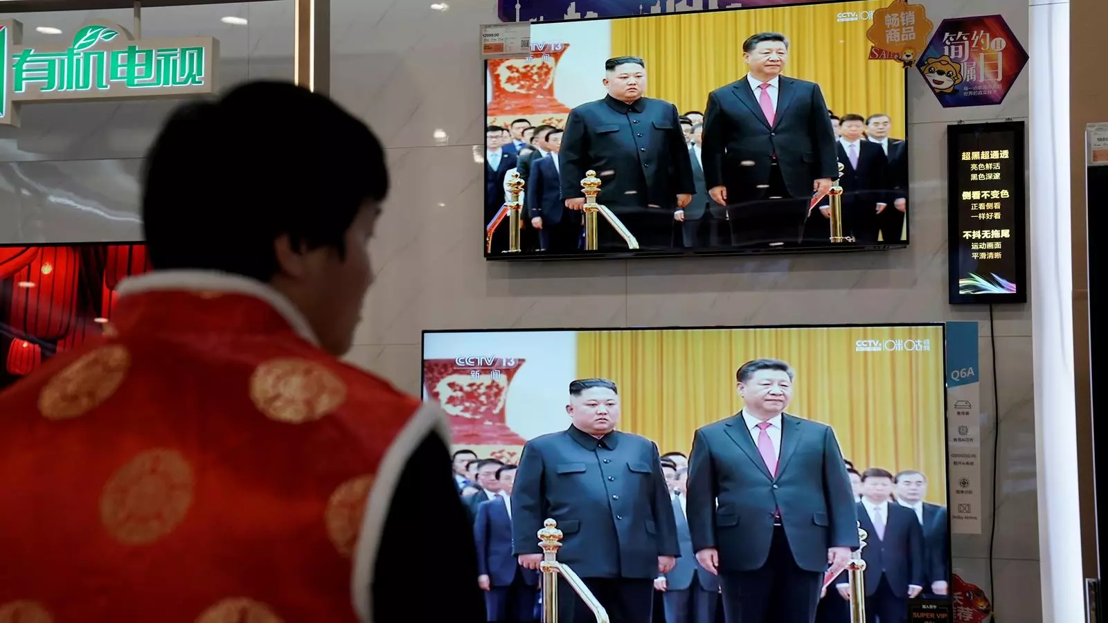 Un home observant la trobada dels líders nord-coreà i xinès en una televisió que es mostra en un aparador de Pequín