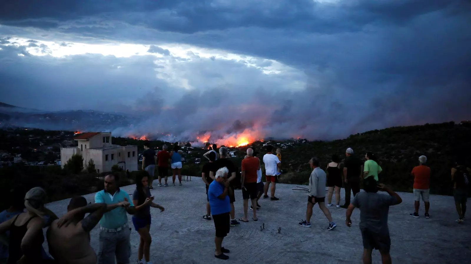 Persones mirant a distància l'incendi de Rafina