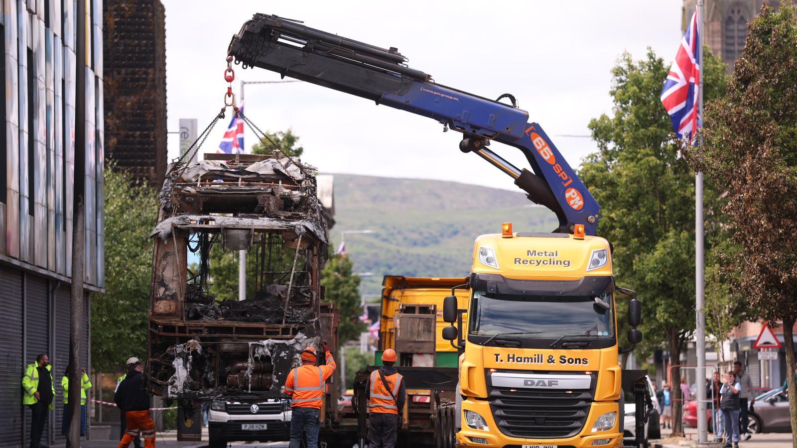 Un autobús es retirado de Newtownards Road, al este de Belfast, después de haber sido incendiado durante los disturbios de la noche del martes contra la inmigración