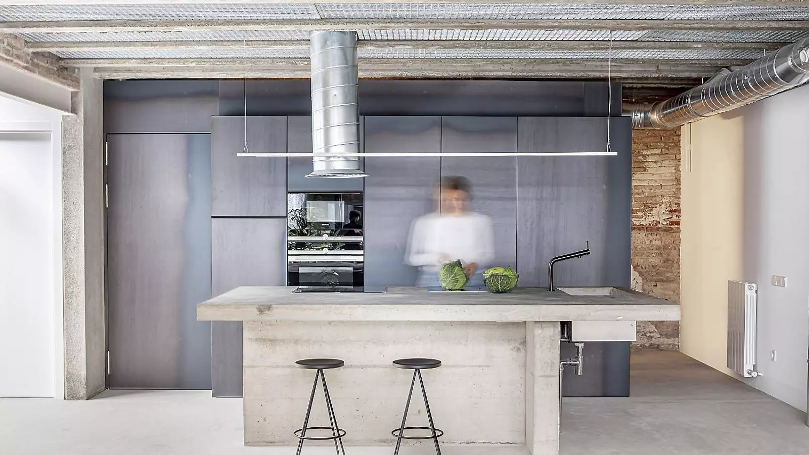 Els arquitectes de CRÜ defineixen La Clara com “una fissura que s’estira fins a les entranyes d’un interior d’illa anàrquic”. I de fet, des del carrer, la casa fa pensar en un garatge amb l’entrada tractada amb més cura. Un cop a dintre, primer l’estudi i seguidament la casa amb els patis aconsegueixen un bon grau d’intimitat entre els edificis que els envolten.