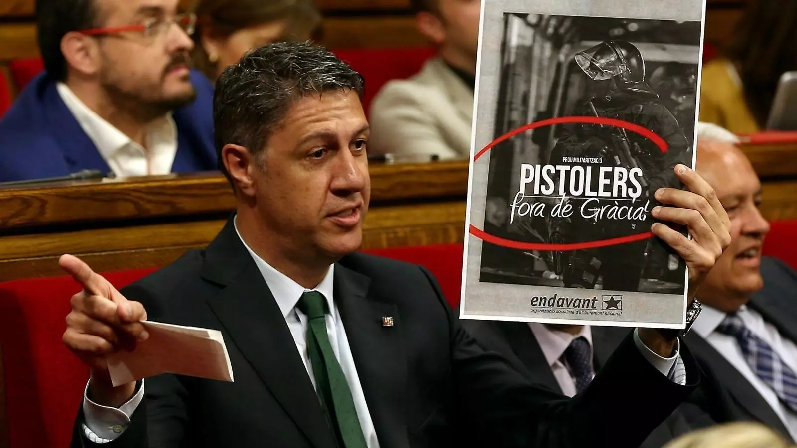 Albiol mostrant un cartell dels aldarulls de Gràcia editat per Endavant, una organització pròxima a la CUP i de la qual forma part Anna Gabriel.