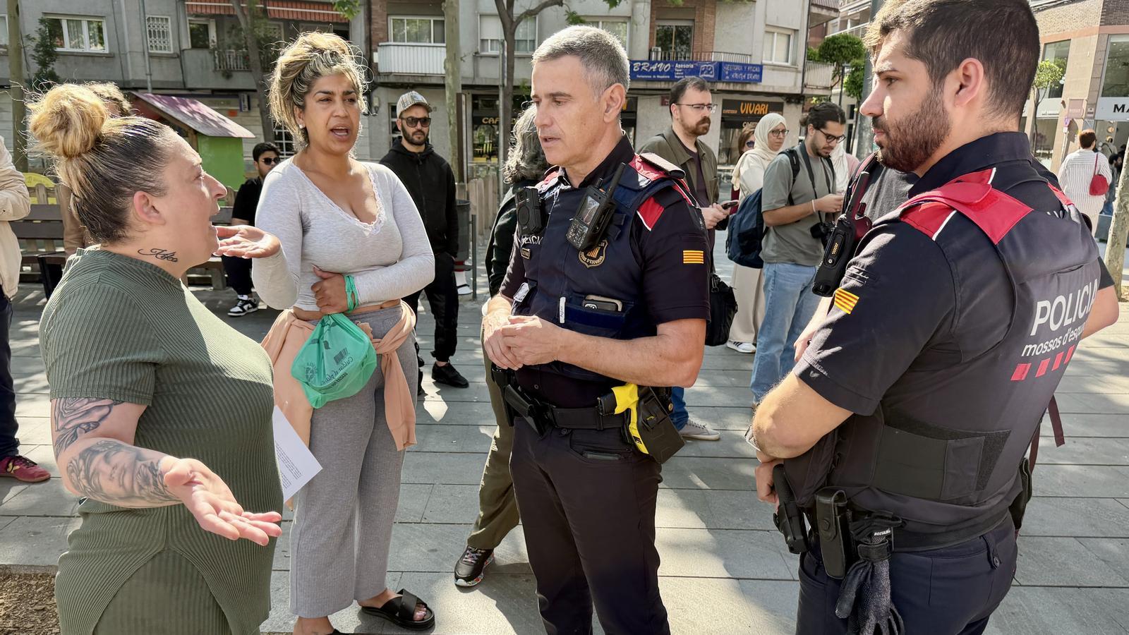 Una patrulla de los Mossos d'Esquadra intenta identificar vecinos de la Mina concentrados frente al Ayuntamiento.