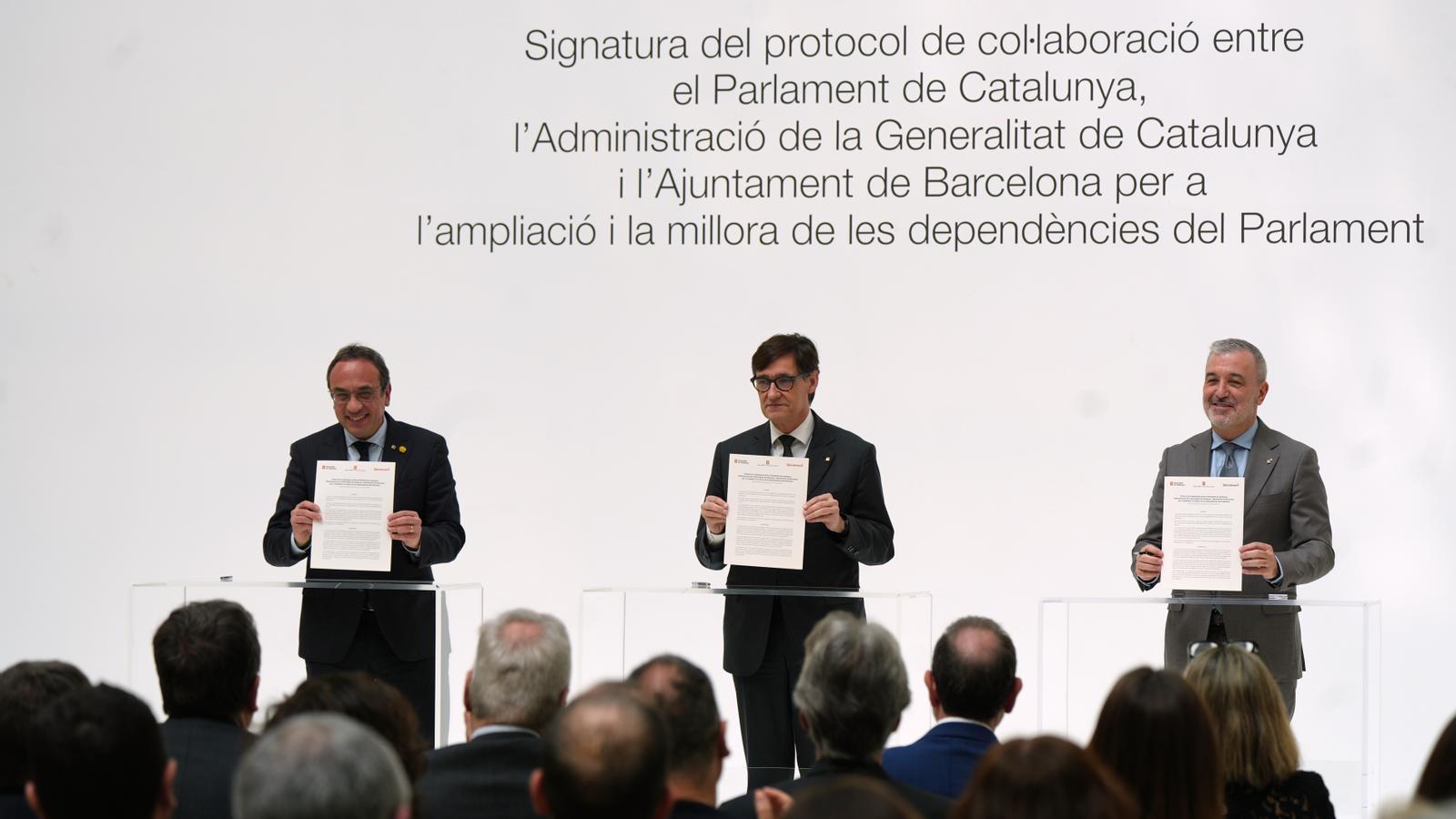 El presidente del Parlament, Josep Rull; el presidente de la Generalitat, Salvador Illa; y el alcalde de Barcelona, Jaume Collboni, en la firma del protocolo de colaboración para ampliar la cámara catalana.