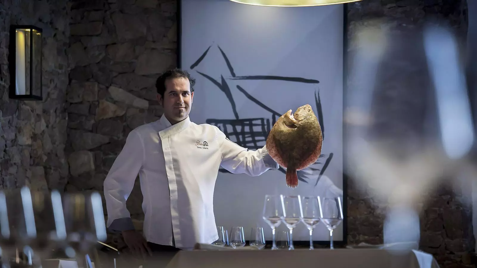 El xef Isaac Sabrià a la sala del restaurant agafant un turbot.