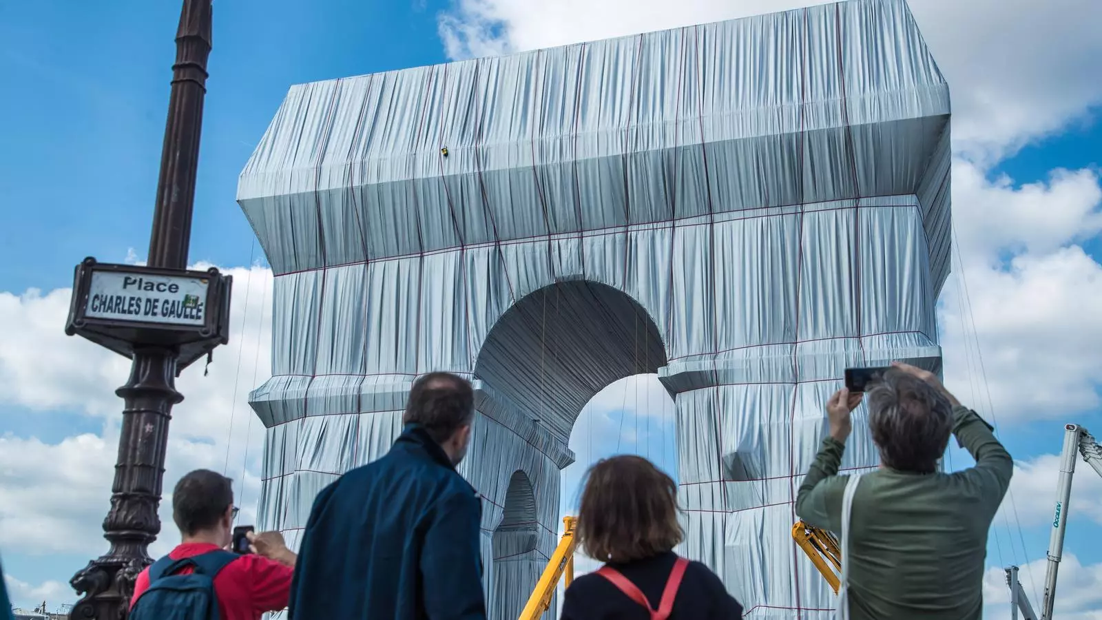 Un grupo de gente observa los últimos preparativos del montaje del envoltorio del Arco de Triunfo como parte de la instalación artística del artista norteamericano Christo, nacido en Bulgaria