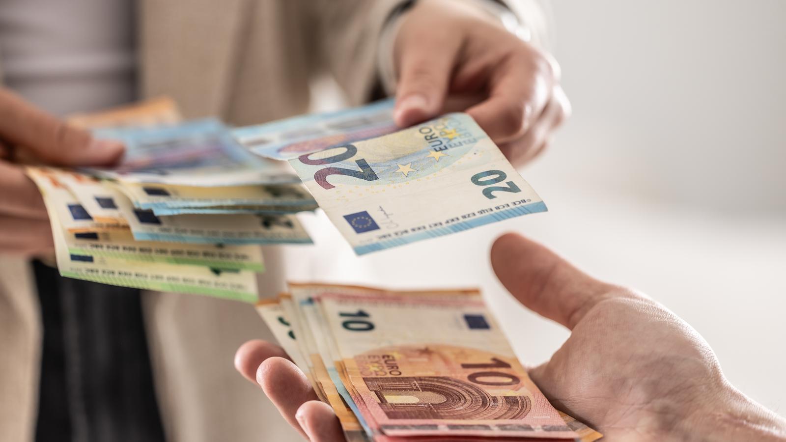 A person paying another person with euro bills.
