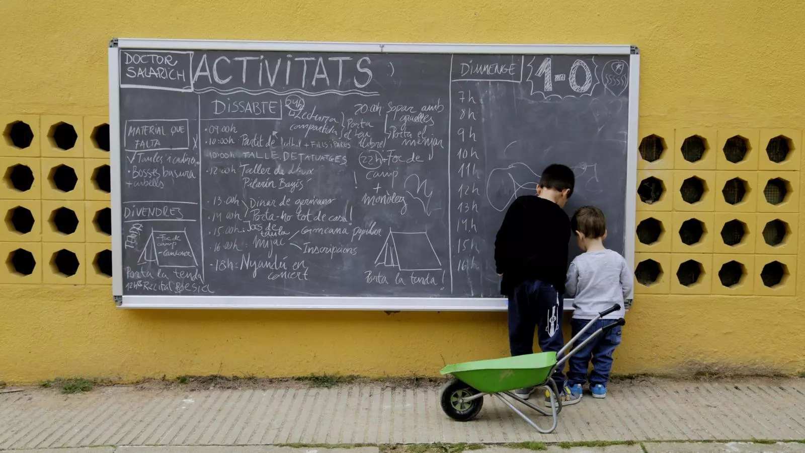 Dos nens miren la pissarra informativa d'activitats a l'Escola Salarich de Vic, el dia abans de l'1-O