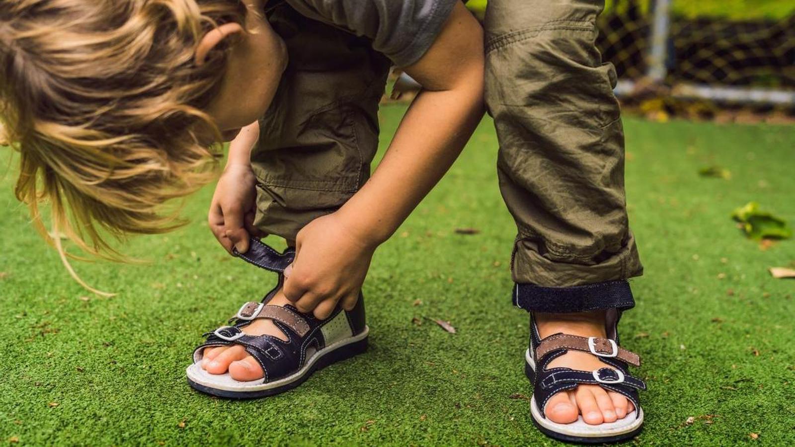 Un niño poniéndose las chanclas.
