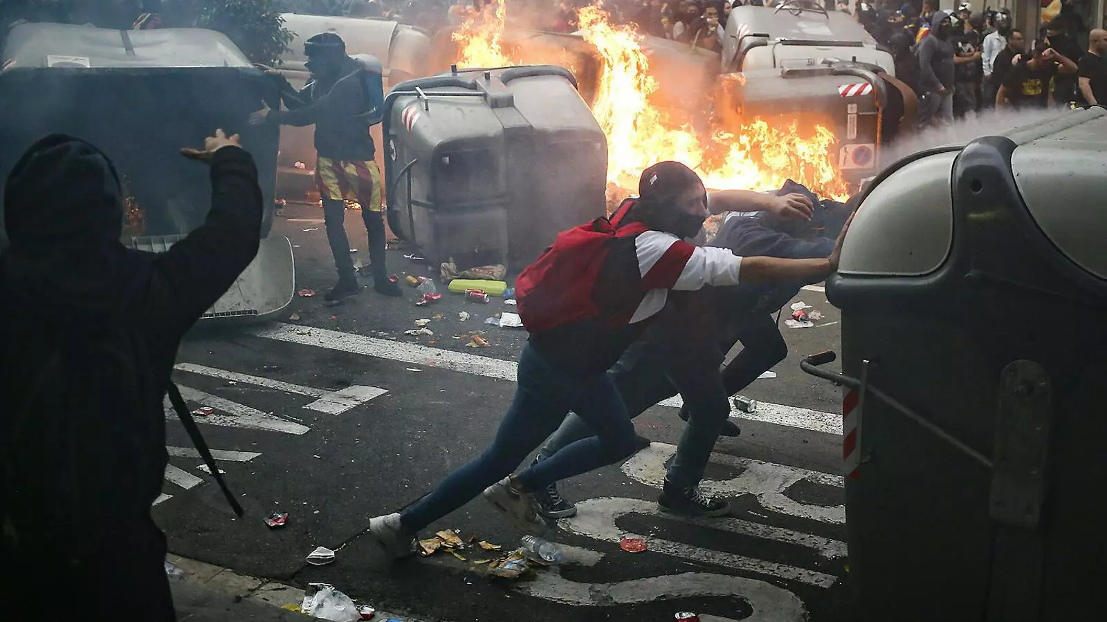 Dos manifestants arrossegant un contenidor a Barcelona divendres.