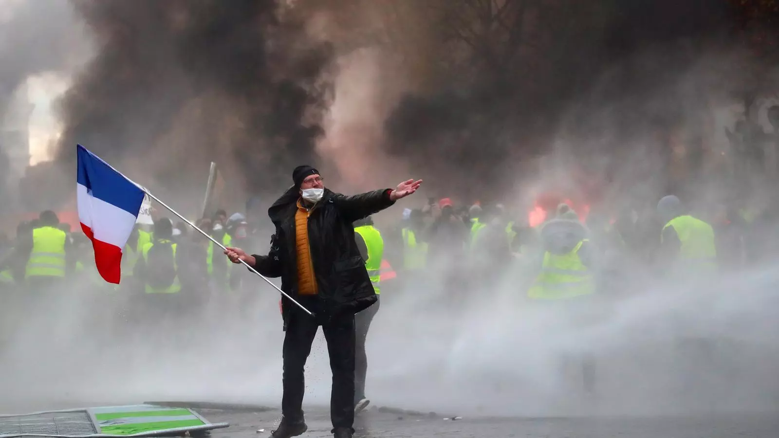 Un manifestant amb la bandera francesa protesta entre el fum de gasos lacrimògens, als parisencs Camps Elisis