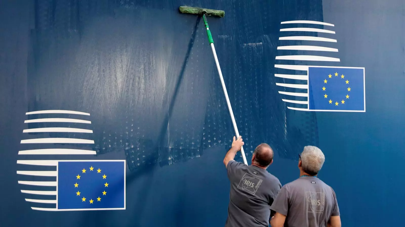 Dos operaris netejant el cartell d'entrada a la Comissió Europea per deixar-la a punt per l'eurocimera
