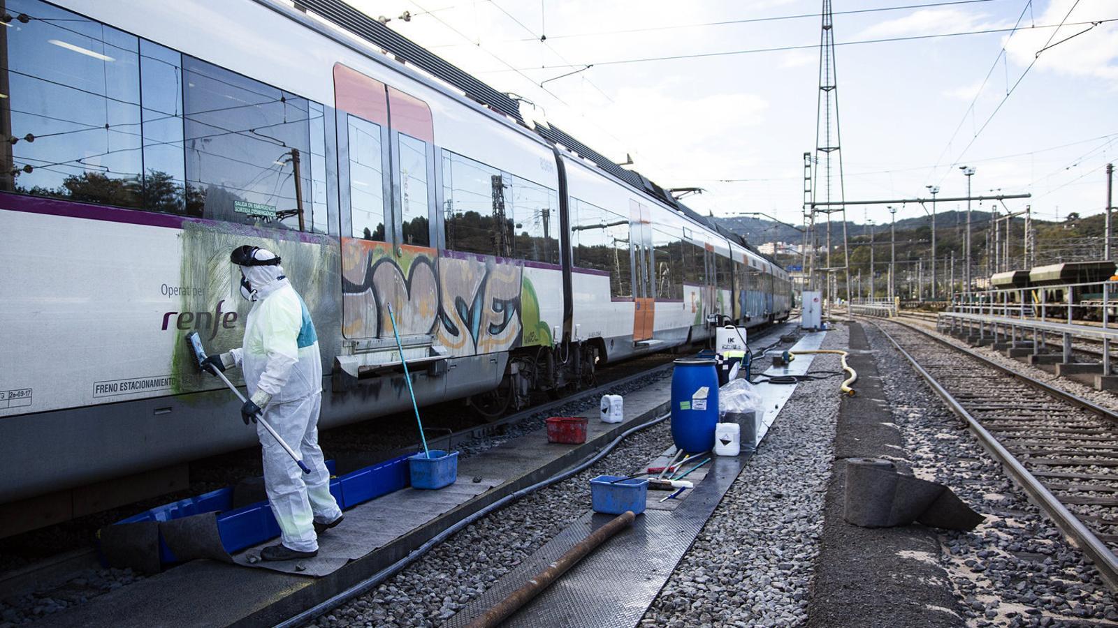 Un operari traient un grafiti d’un vagó a l’estació de Rodalies de Montcada i Reixac - Bifurcació.