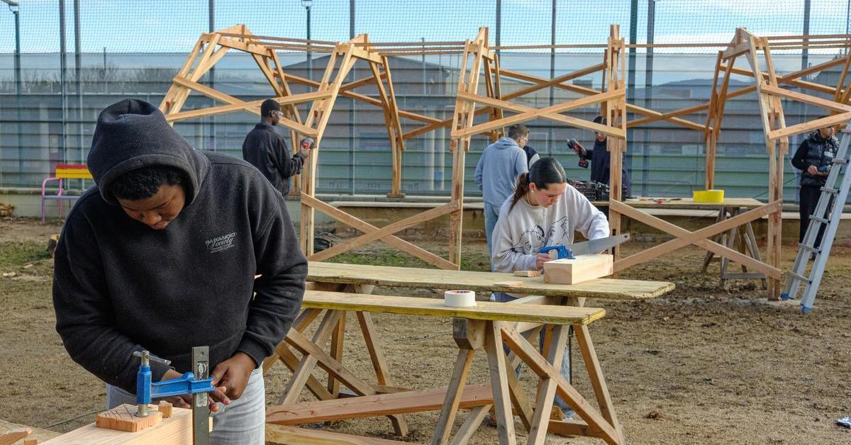 Els alumnes que construeixen l’ombra del pati amb les mans