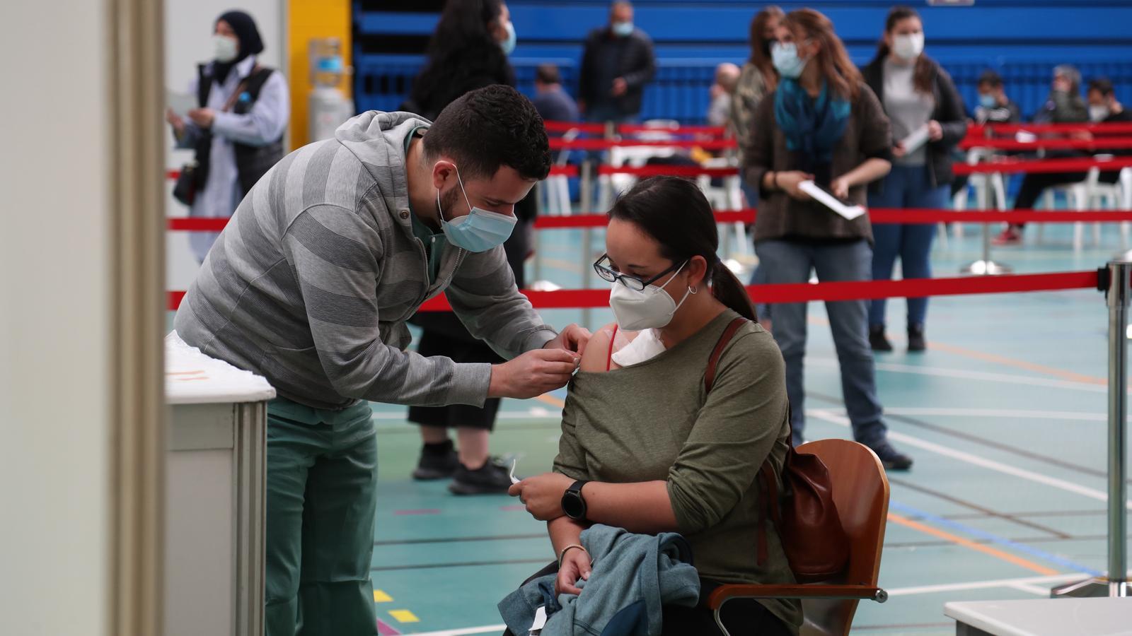 Una infermera vacuna una dona al punt de vacunació massiva del poliesportiu germans escales.