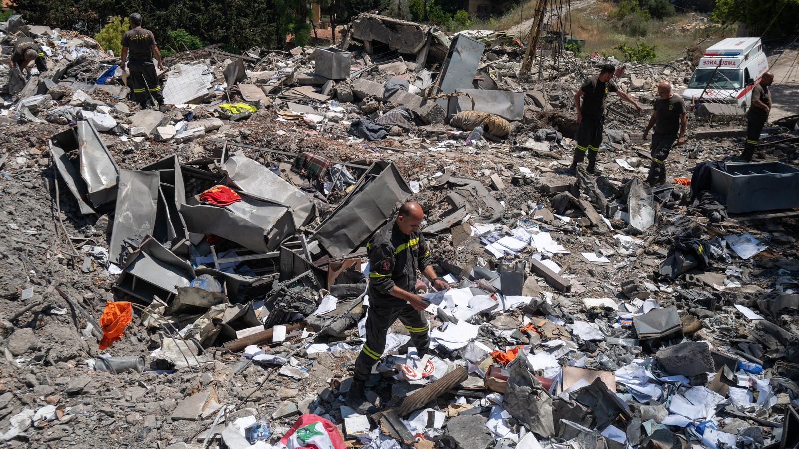 Miembros de la Defensa Civil libanesa, organismo dedicado a la extinción de incendios, primeros auxilios y rescate, buscan sus pertenencias entre los escombros en Nabatieh, Líbano.