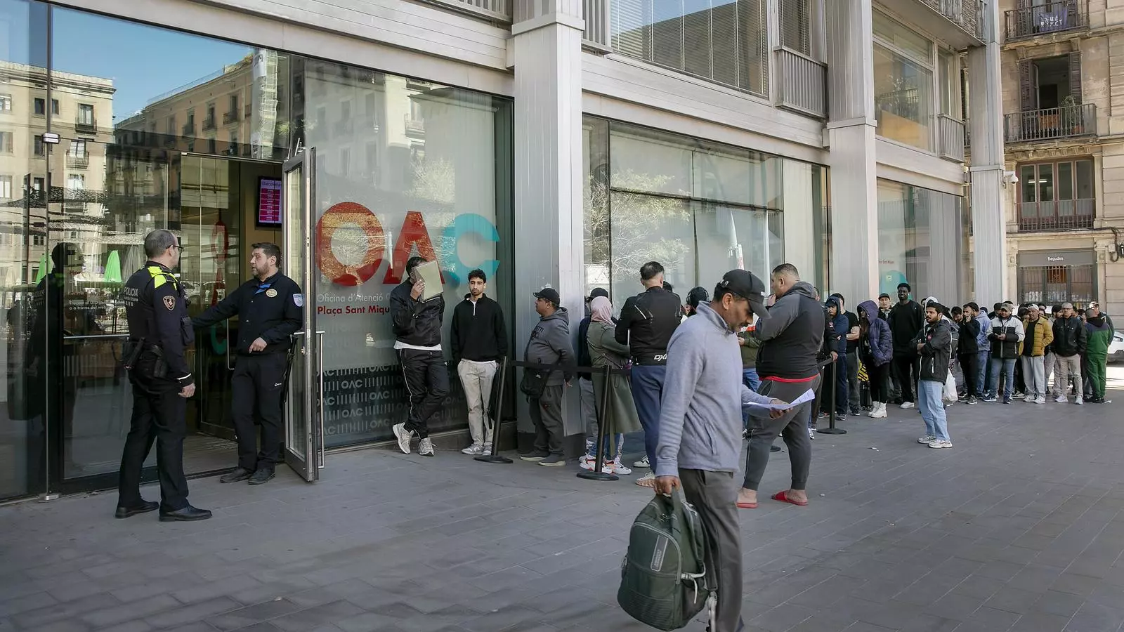 Cues davant de l'oficina d'atenció ciutadana per presentar papers per la regularització