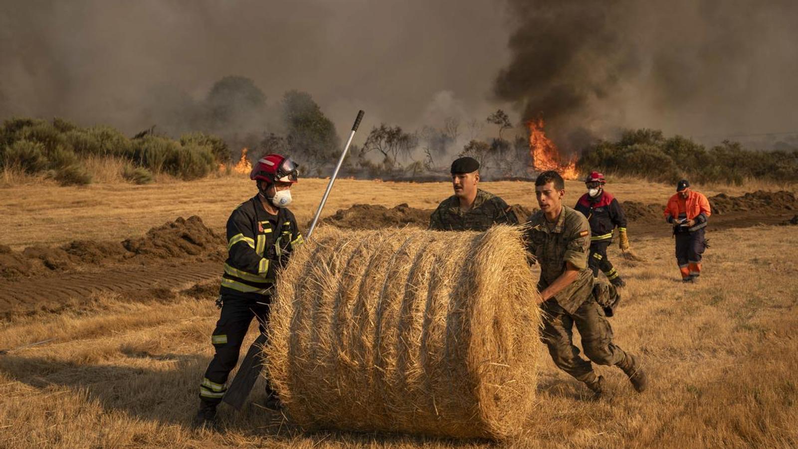 Soldiers and firefighters remove straw bales from a cultivated field in A Gudiña, in the province of Ourense.