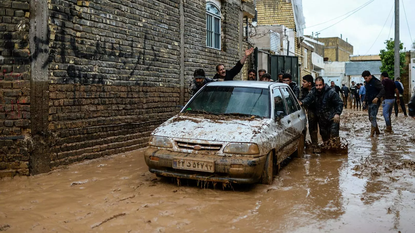Homes intenten empènyer un vehicle a la ciutat de Xiraz, que ha quedat inundada.
